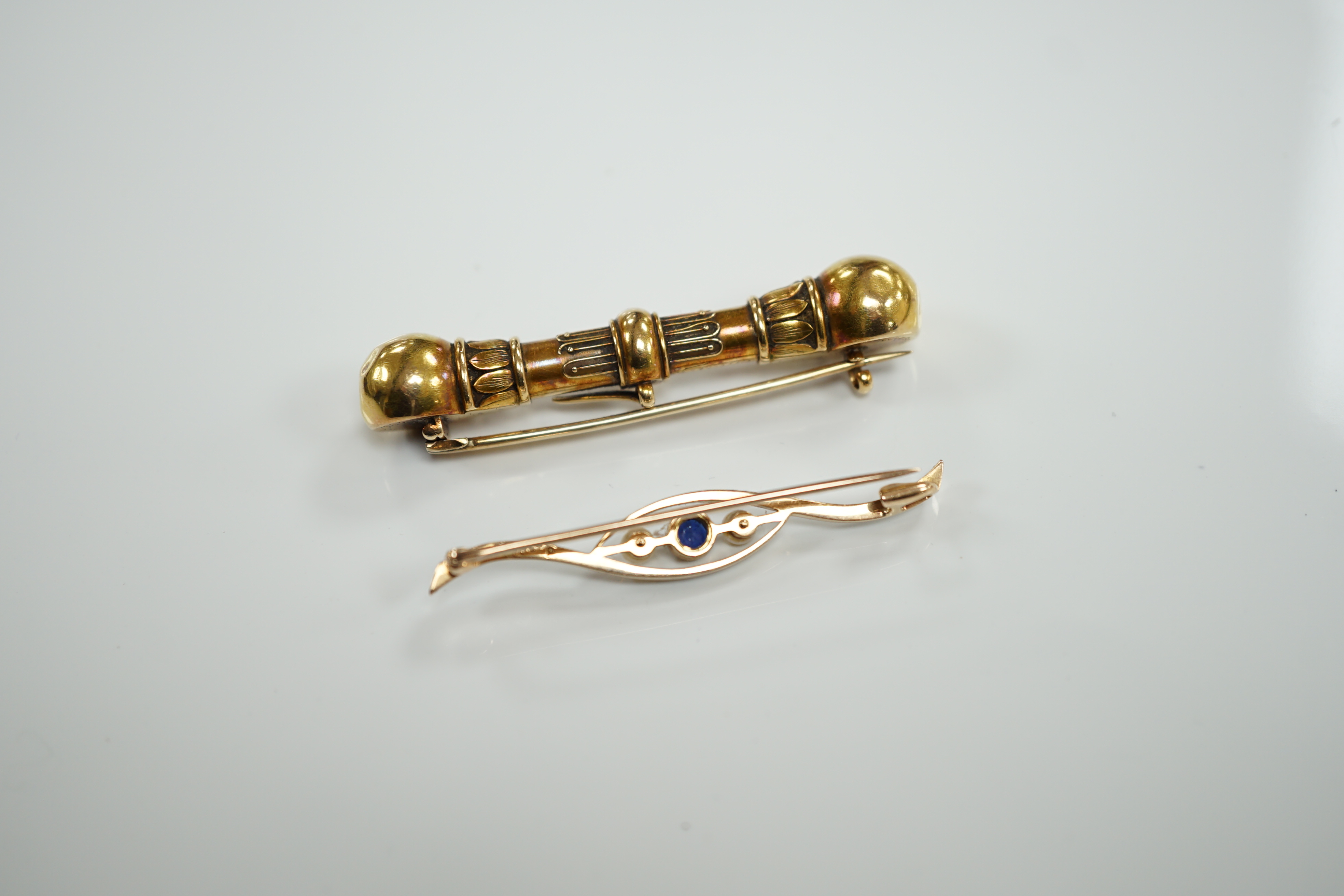 A Victorian yellow metal 'dumbbell' bar brooch, with engraved inscription dated 1862, 56mm and a later 15ct, sapphire and seed pearl set three stone crossover bar brooch.